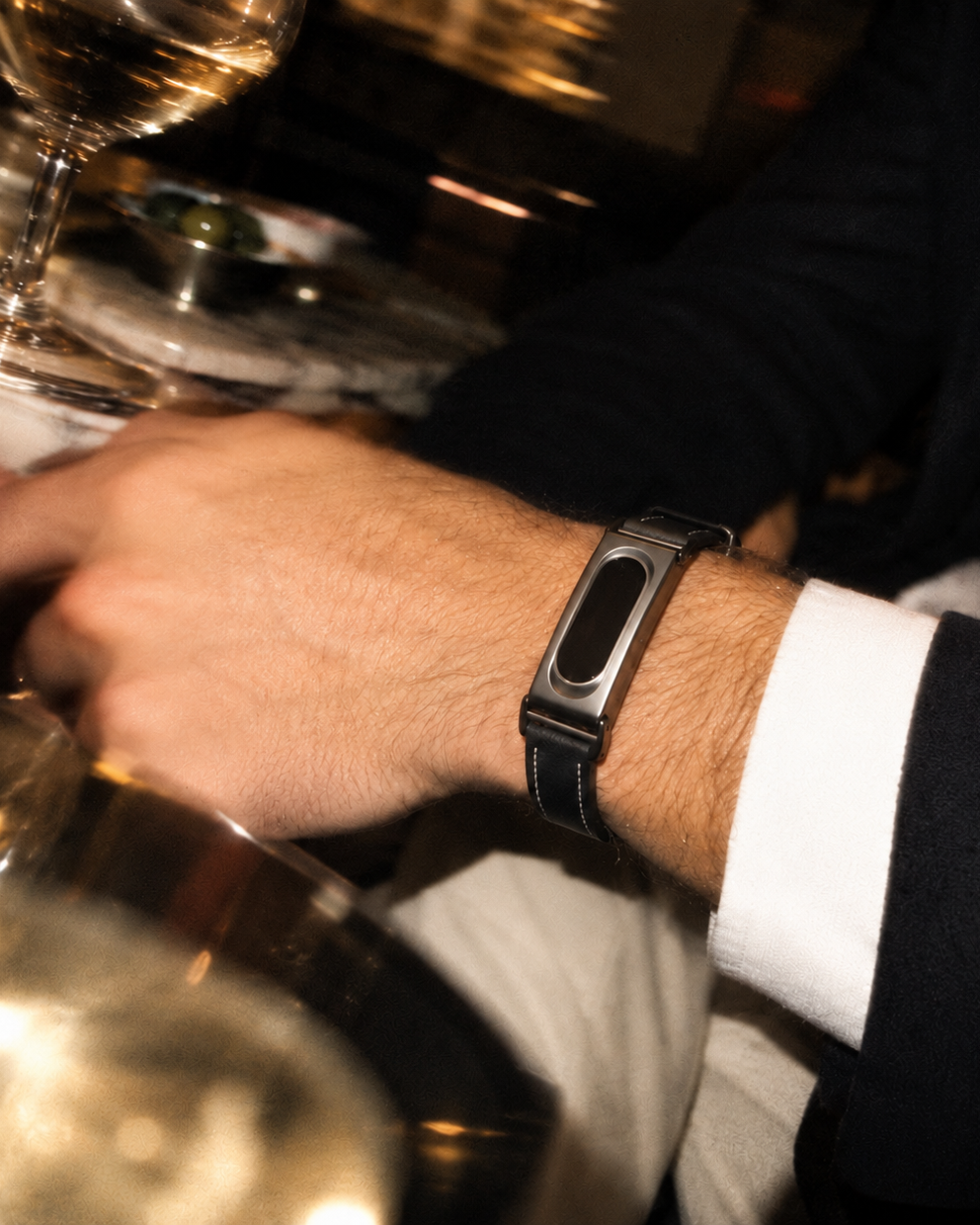 The Prenup band in Black vegan leather with a metal case, worn with a shirt cuff