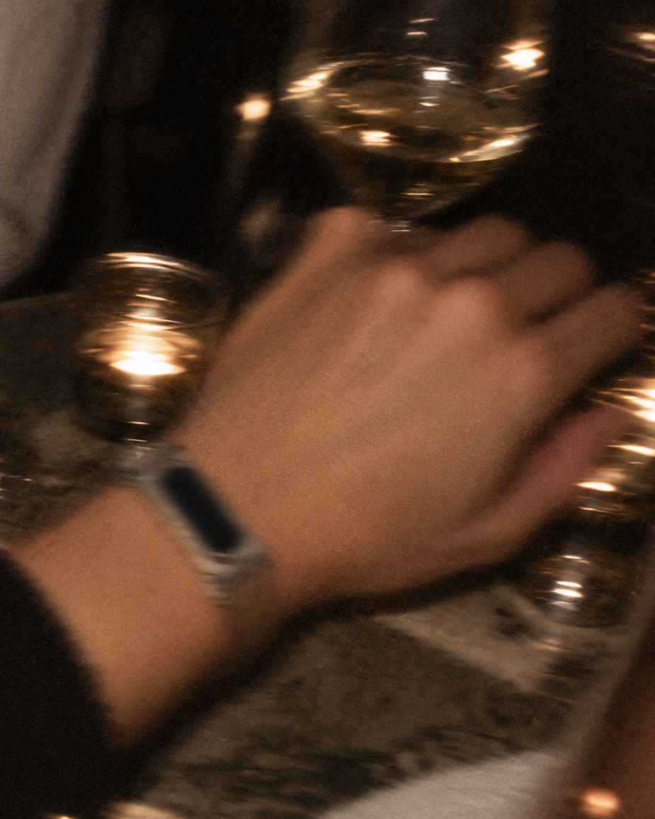 The Prenup band in Beige vegan leather with a metal case, on the wrist by candlelight