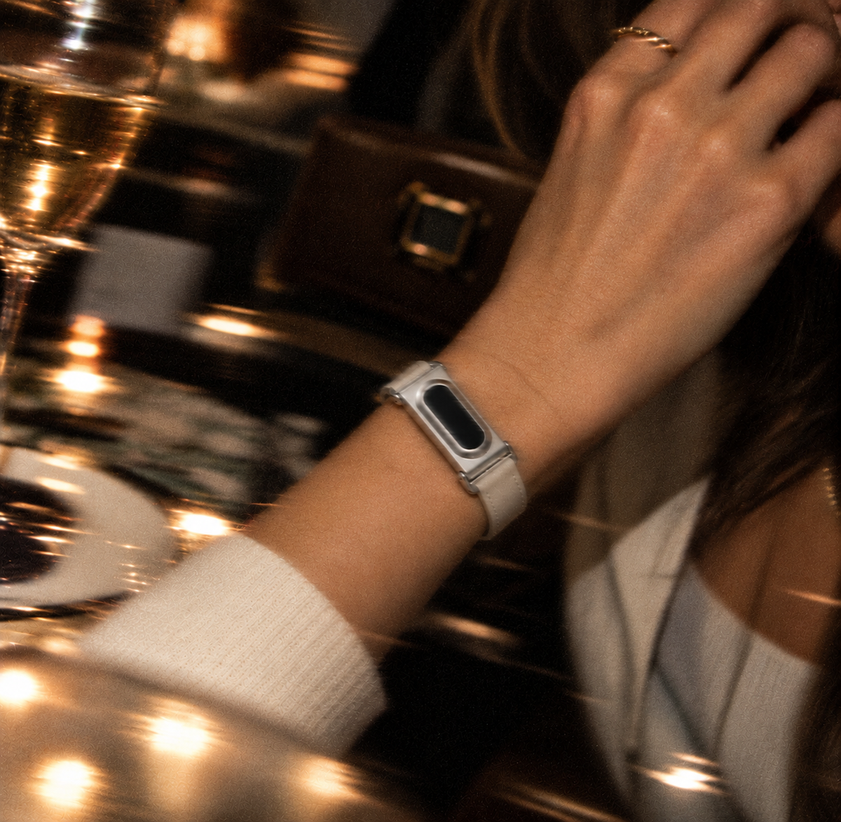 The Prenup band in Beige vegan leather with a metal case, worn at dinner, compatible with Google Fitbit Air